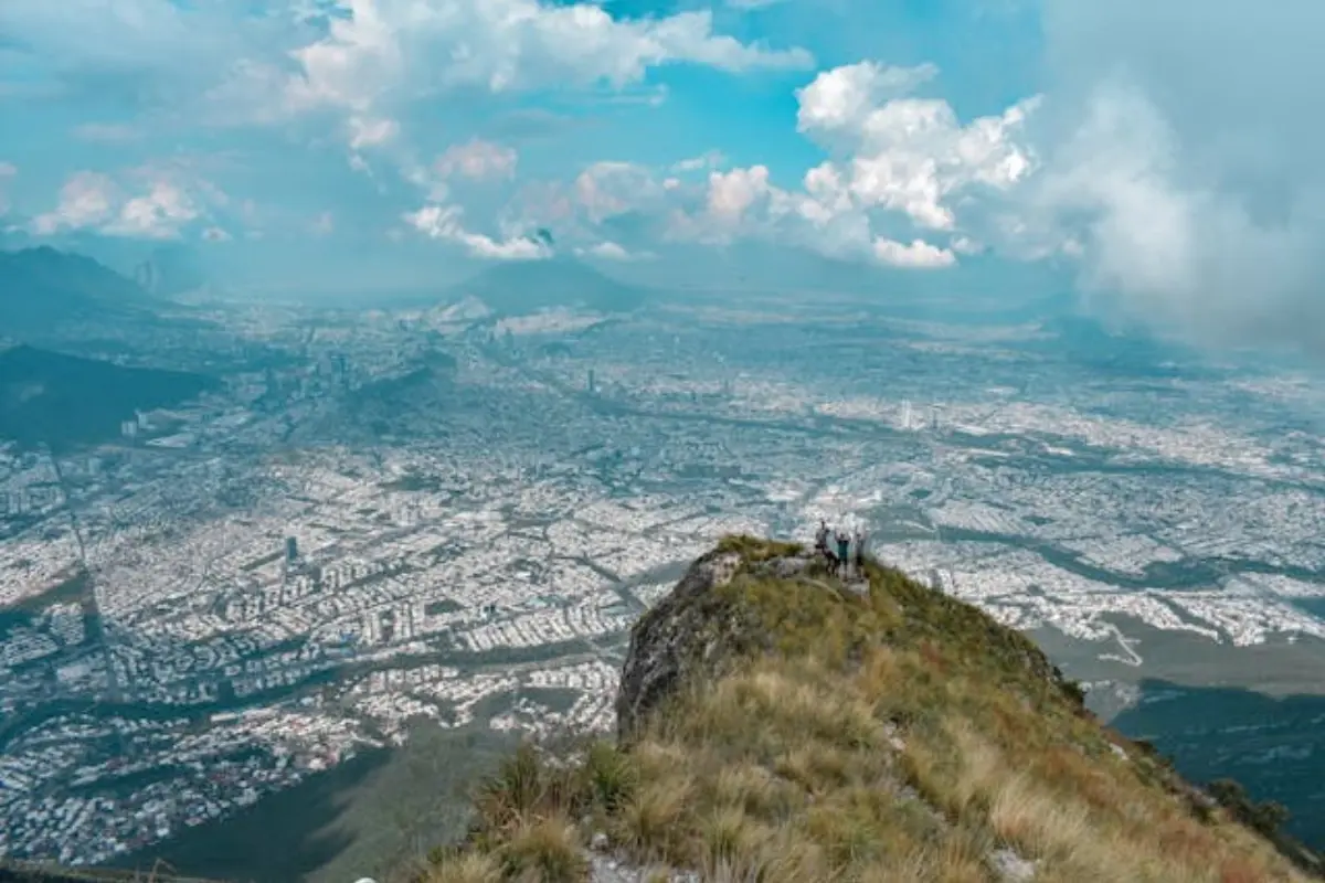 Ciudad de Monterrey, se ve desde un lugar natural alto donde hay algunas personas. Es de día y el cielo está nublado