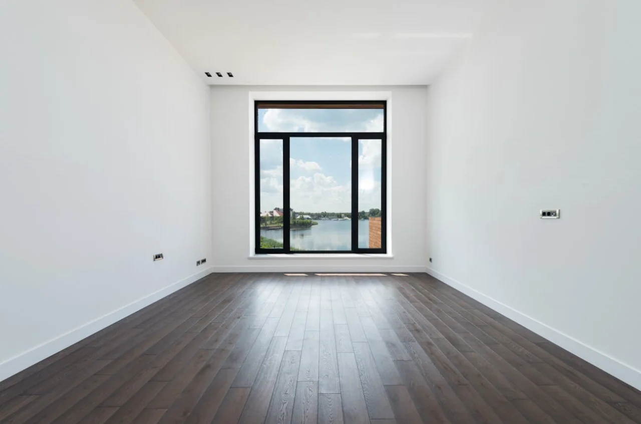 el cuarto de un departamento, se ve una ventana iluminada por la que puede observarse un lago