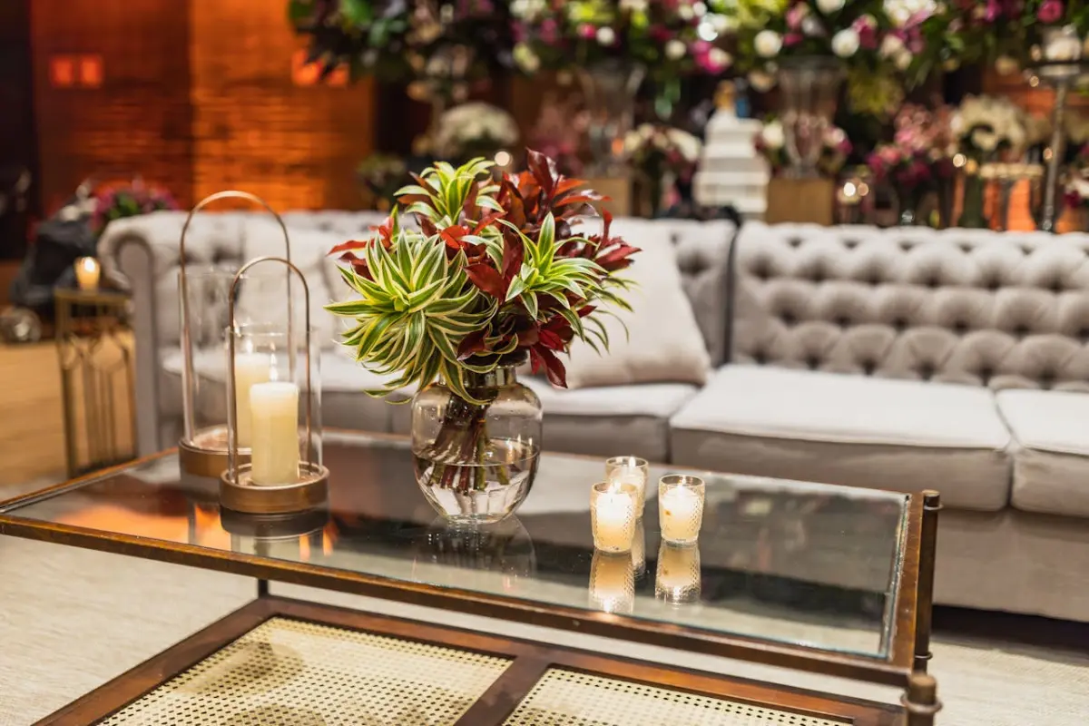 Sala de una casa con un sillón, una mesa en la que están unas velas y un florero.