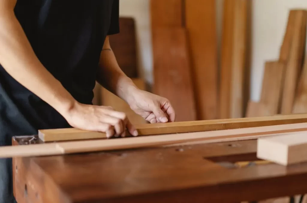 Las manos de una persona midiendo un trozo de madera