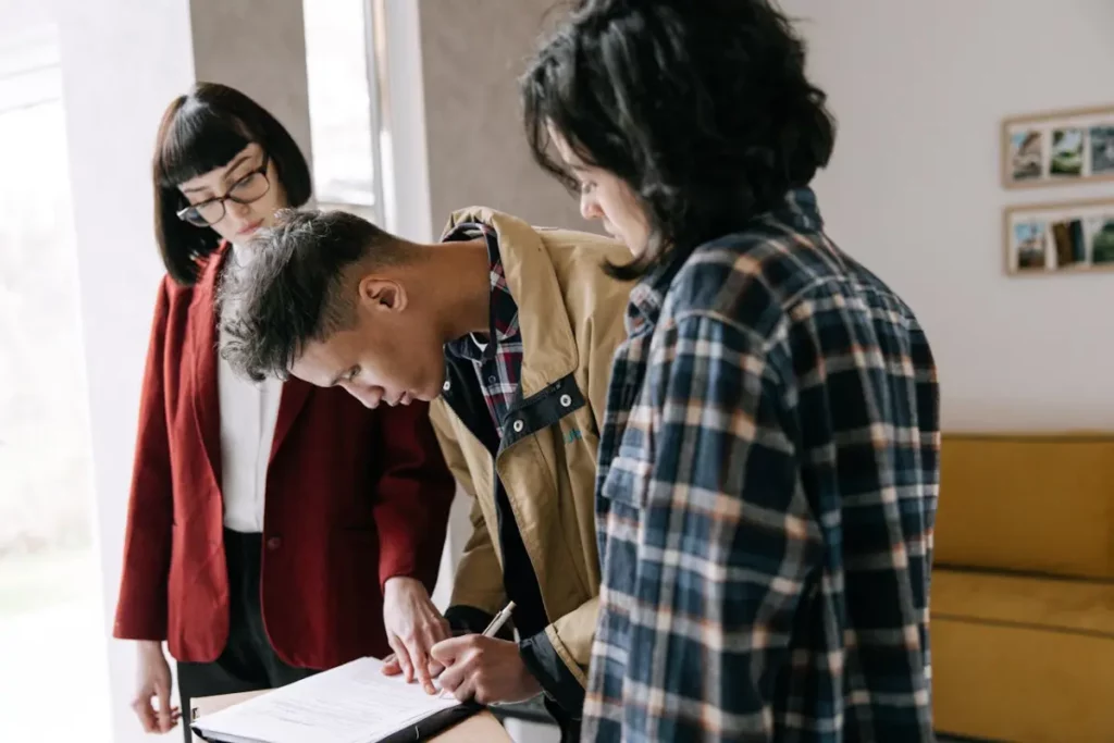 Dos mujeres y un hombre extranjero que firma un documento