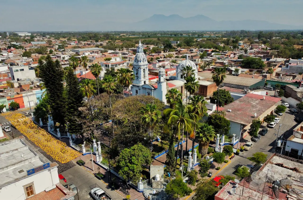 Vista desde arriba de una parte de Jalisco. Hay una iglesia, árboles, casas y automóviles