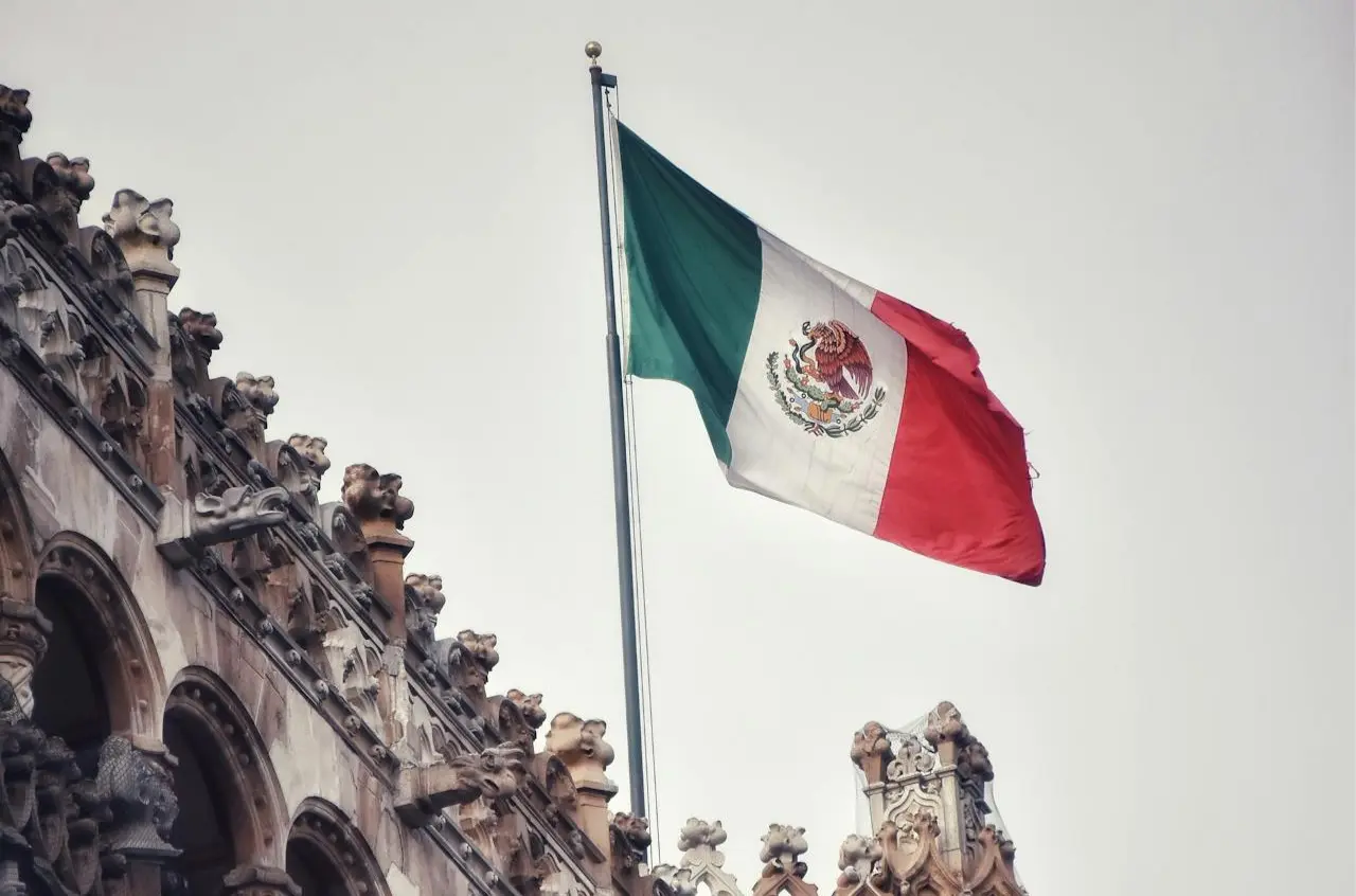 Bandera de México sobre una estructura arquitectónica de la que solo se ve una pequeña parte